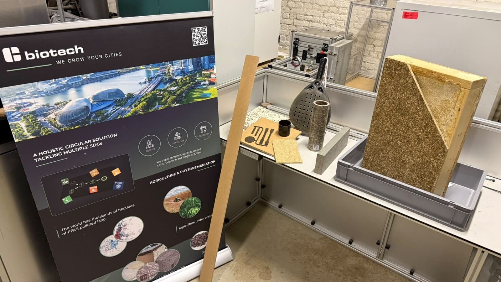 Workbench in the biomaterials lab with sample sheets made from plant fibres, pressed samples and a biotech partner's banner.